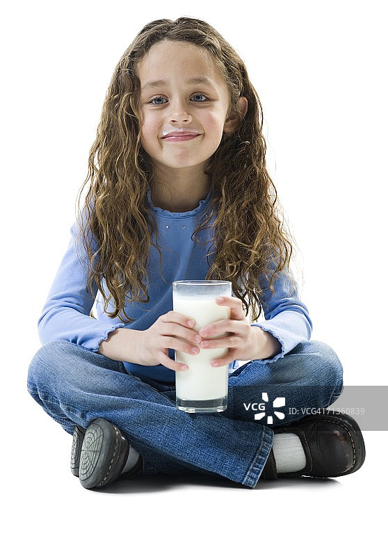 一个女孩坐在地板上，拿着一杯牛奶的肖像图片素材