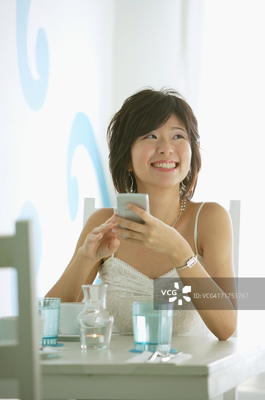 一个女人坐在咖啡馆里，捧着粉盒，面带微笑图片素材