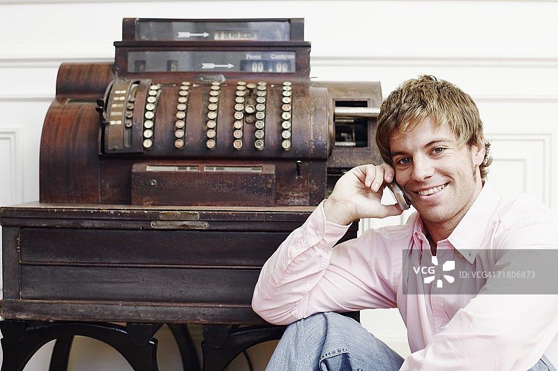 一个年轻人在打字机旁边用手机说话的肖像图片素材