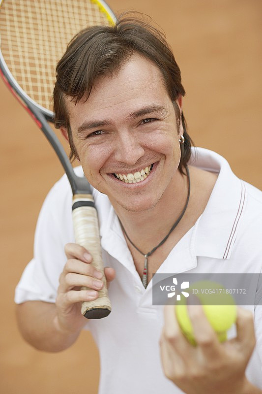 一个中年男人的肖像，拿着网球和网球拍图片素材