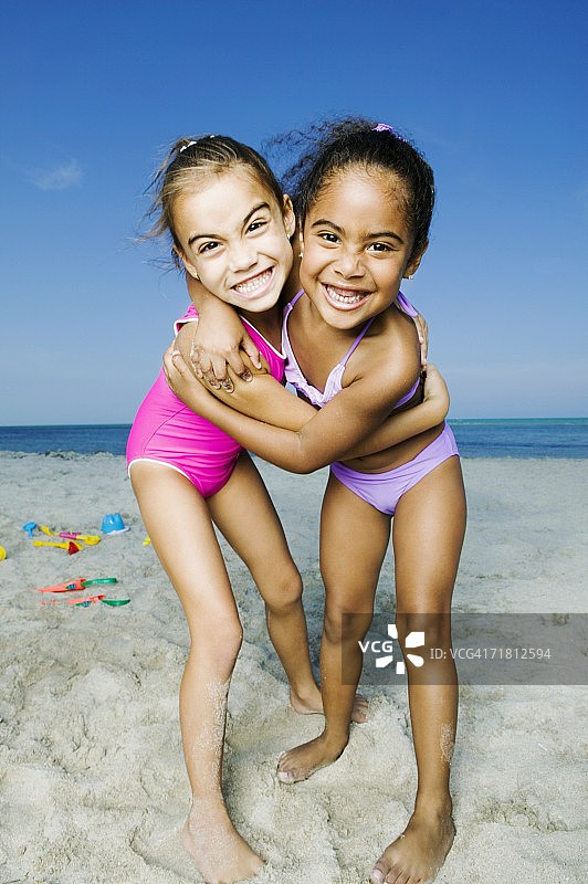 两个女孩在海滩上拥抱的照片图片素材