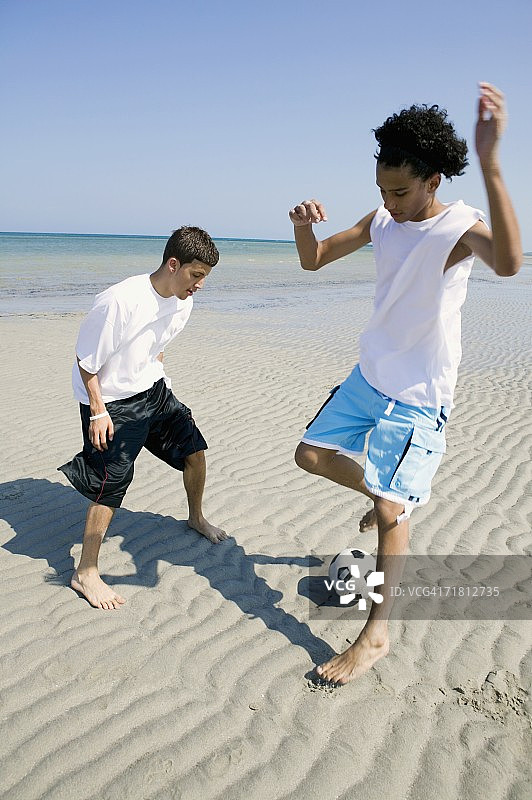 两个十几岁的男孩在沙滩上玩足球图片素材