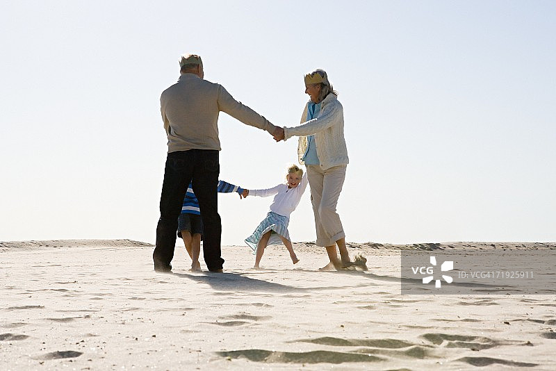 爷爷奶奶和孙子孙女在沙滩上跳舞图片素材