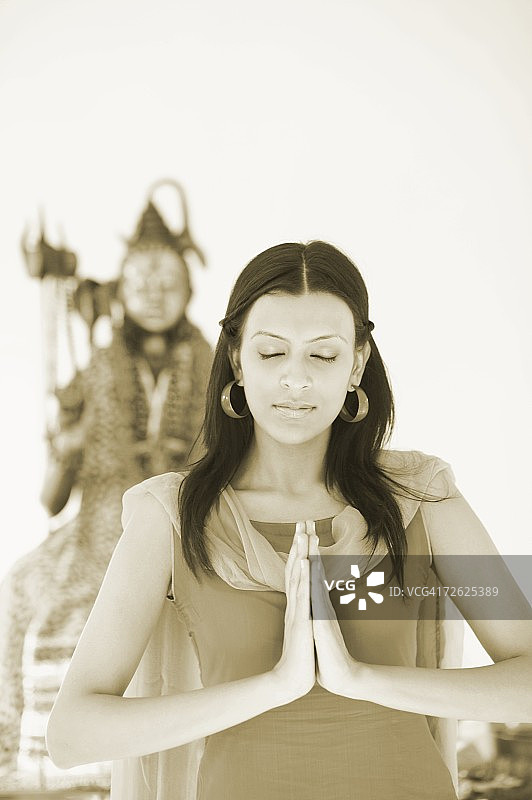 一个年轻女人的特写站在一个祈祷的位置在一个神像的主湿婆图片素材