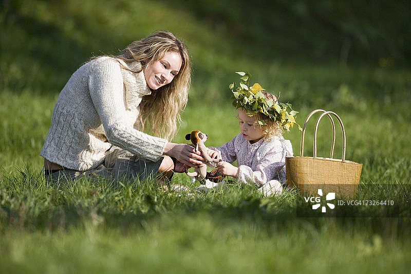 母亲和女儿在草地上，女儿戴着花环图片素材
