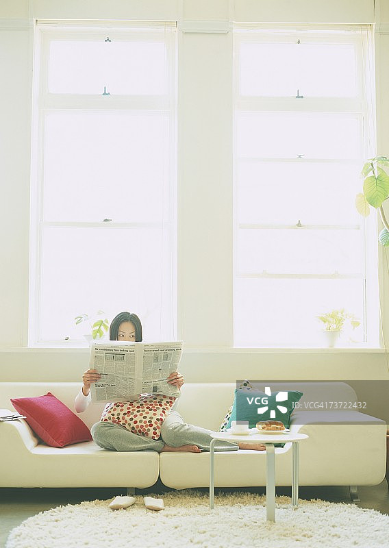 坐在沙发上看报纸的女人图片素材
