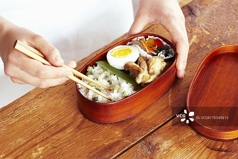 用筷子夹着饭盒吃的男人，手的特写图片素材