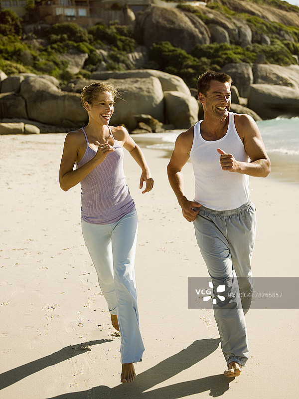 一对夫妇在沙滩上奔跑。图片素材