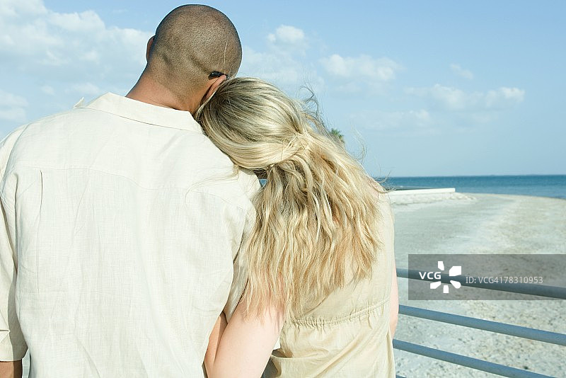 两个人手挽着手站在一起看风景，女人的头靠在男人的肩膀上，背影图片素材