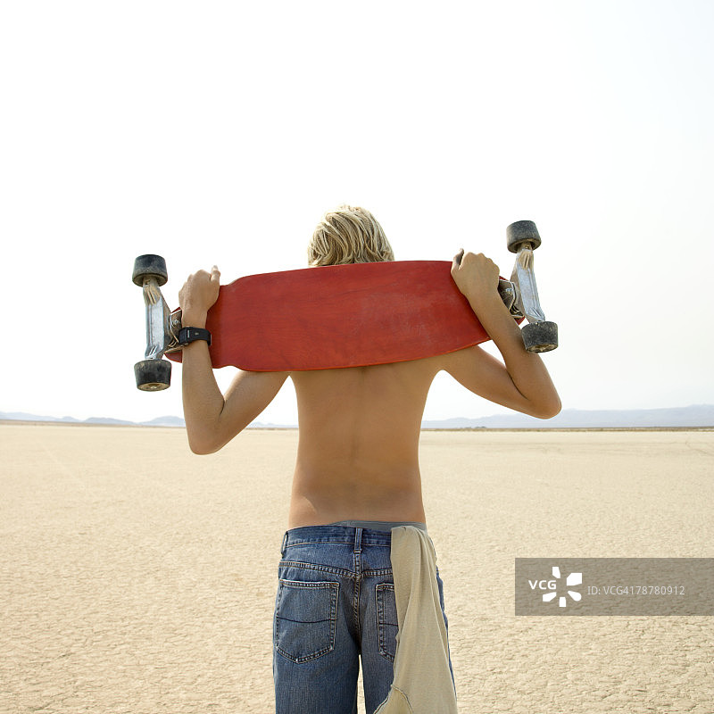 在沙漠里玩滑板的少年图片素材
