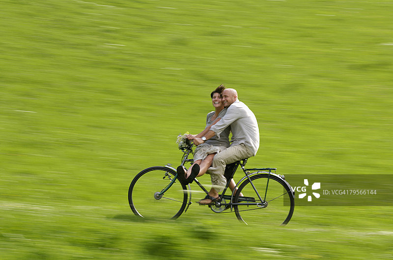 情侣在草地上骑自行车图片素材