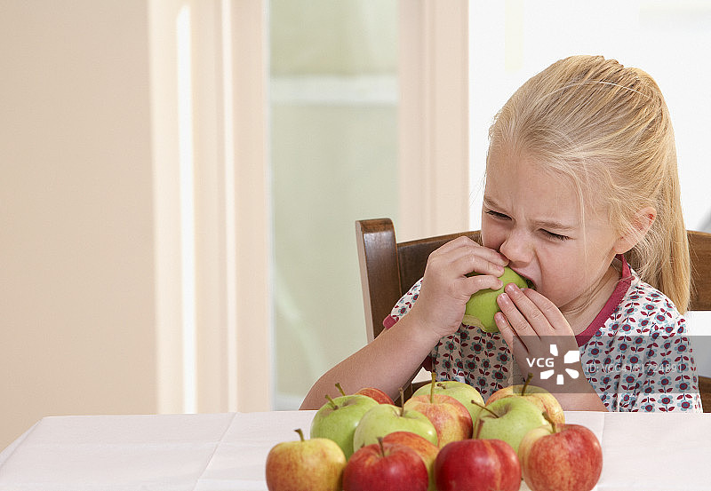 小女孩在厨房里吃苹果图片素材