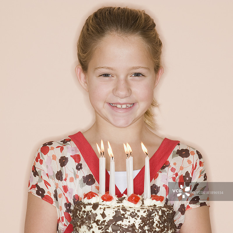 女孩拿着生日蛋糕和点燃的蜡烛图片素材