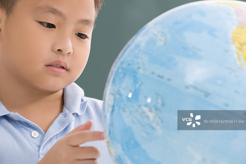 一个男孩看地球仪的特写图片素材
