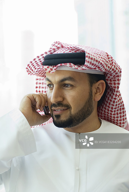 阿联酋迪拜，一名穿着传统中东服饰的男子在电话上的肖像图片素材