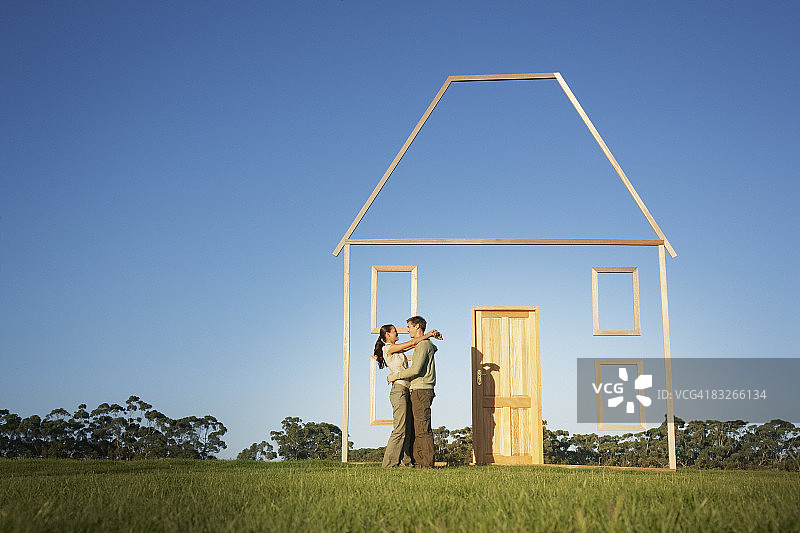 夫妇拥抱旁边的垂直房子轮廓图片素材