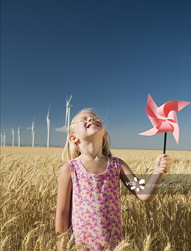 微笑的女孩拿着风车在风电场图片素材
