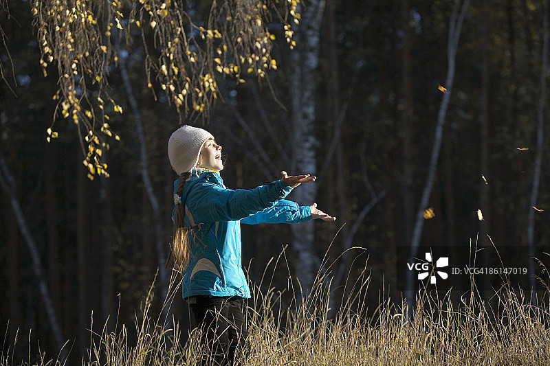 一个年轻的女孩在田里摘树叶图片素材