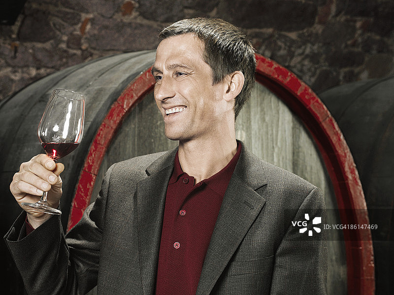葡萄酒商微笑着拿着一杯红酒图片素材