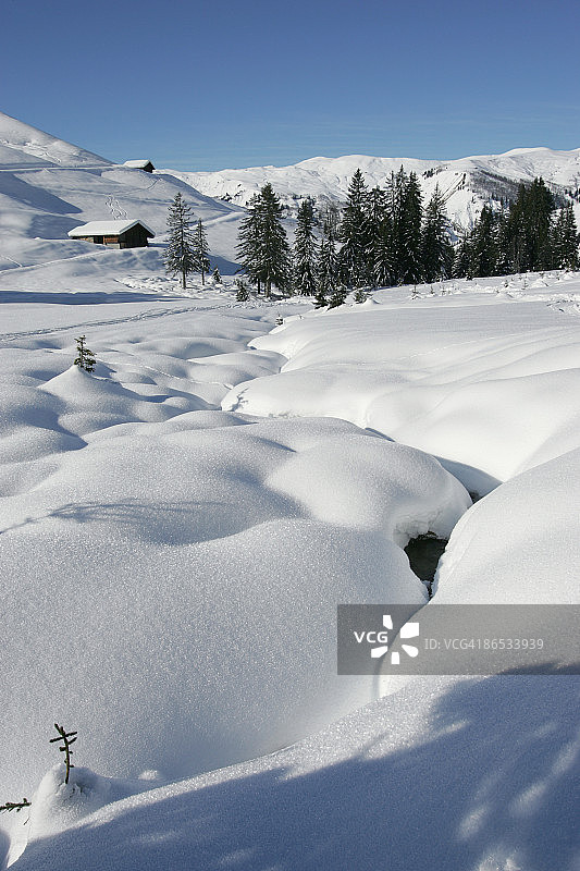 白雪覆盖的山坡上的小屋图片素材