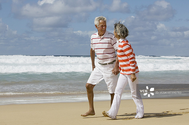 一对成熟的夫妇在海滩上手拉手散步图片素材