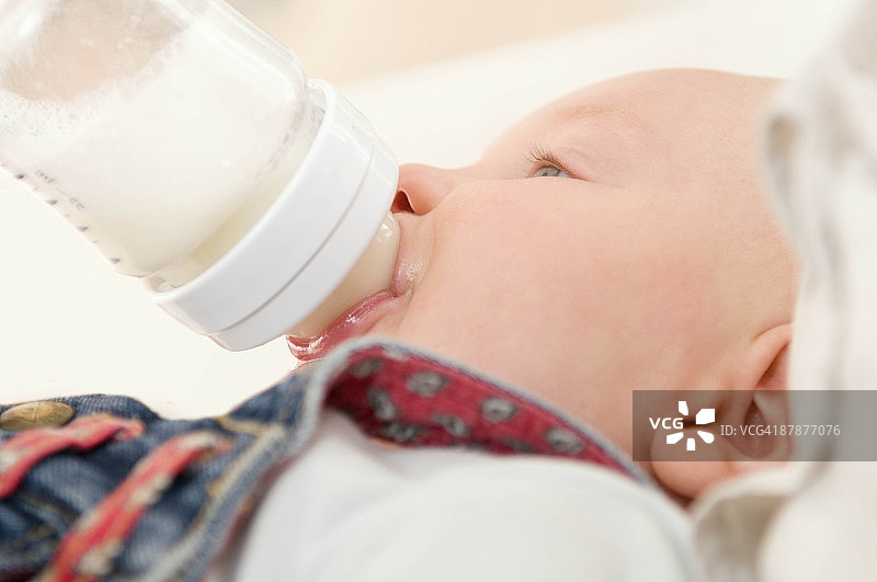 一个婴儿喝着一瓶牛奶，很放松图片素材