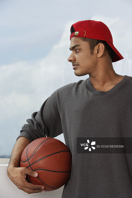 年轻人戴着红帽子，拿着篮球图片素材