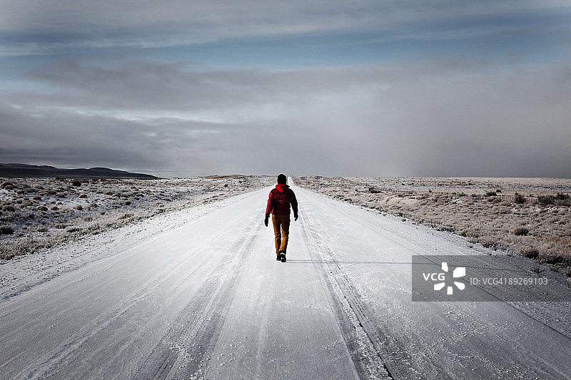 一个女人走在白雪覆盖的荒无人烟的路上图片素材