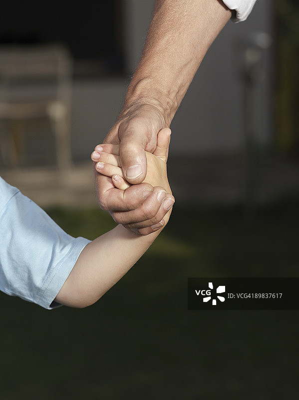 一个小孩和一个男人牵着手的细节图片素材