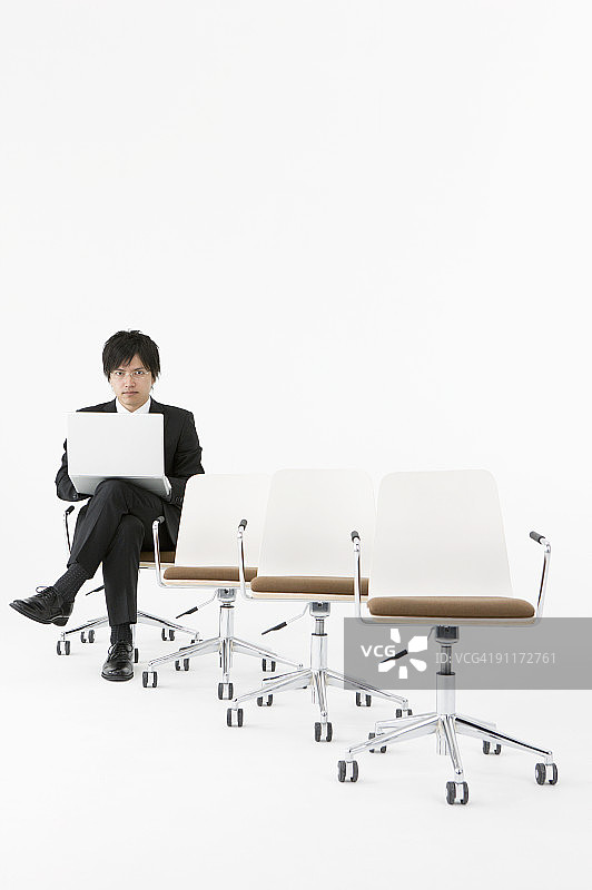 坐在椅子上使用笔记本电脑的商人图片素材