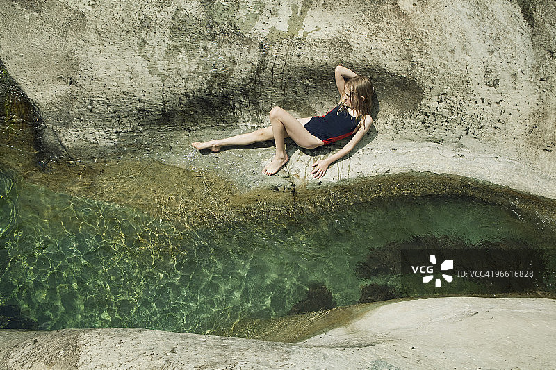 女孩躺在小溪边的岩石上图片素材