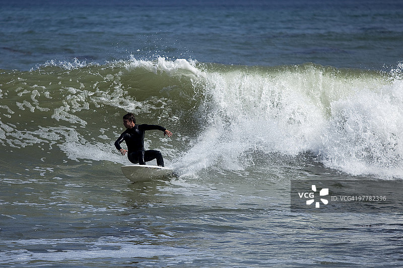 一名男性冲浪者在波浪上咄咄逼人地雕刻。图片素材