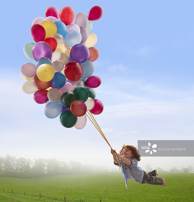 抱着气球的男孩，漂浮在田野上空图片素材
