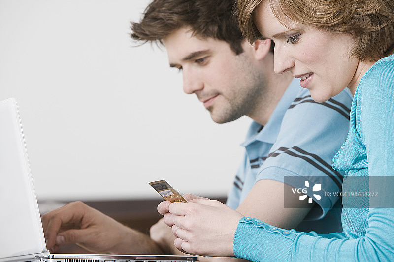 年轻夫妇在笔记本电脑前刷卡图片素材