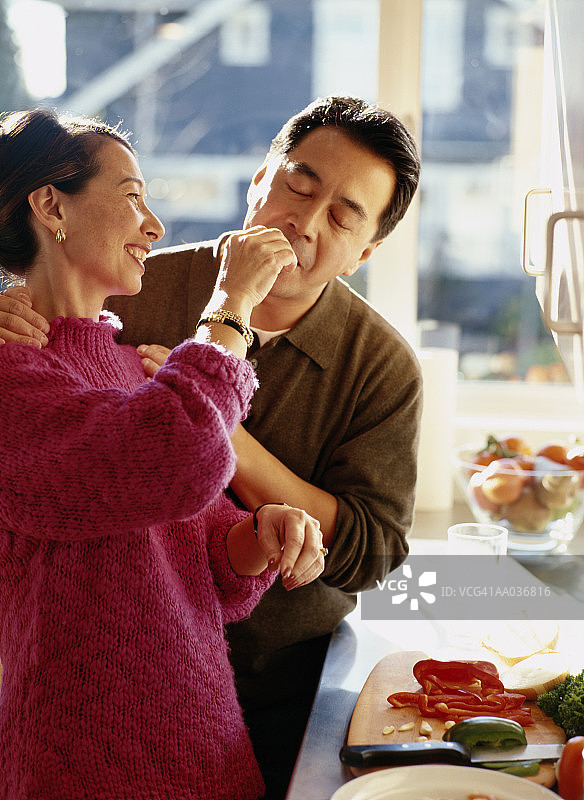 成熟夫妇在厨房，女人喂男人吃东西图片素材