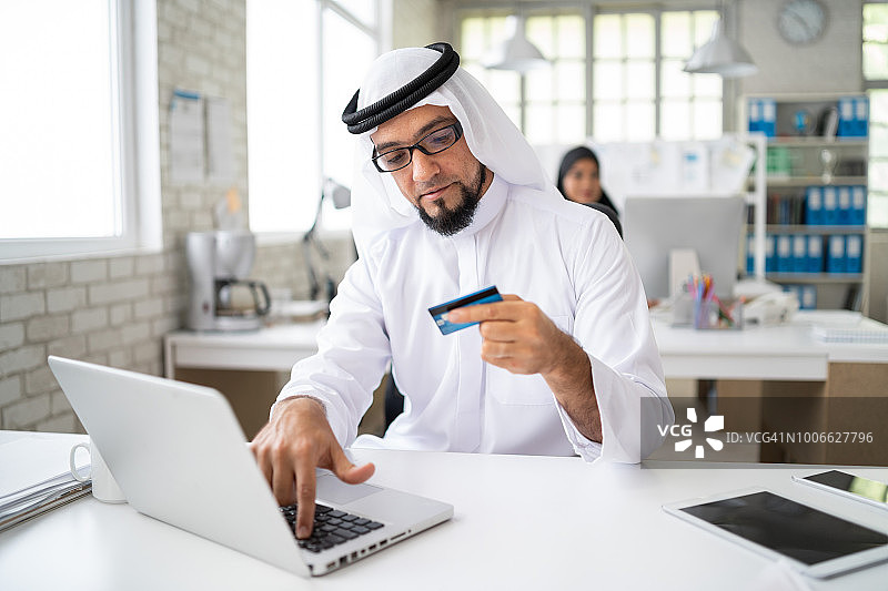 阿拉伯商人在现代办公室用信用卡购物图片素材
