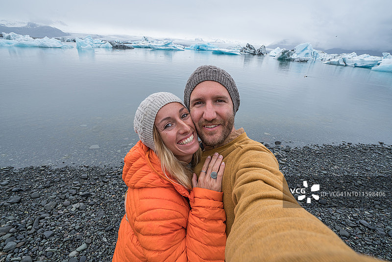 年轻夫妇与冰川泻湖自拍，冰山浮在水上图片素材