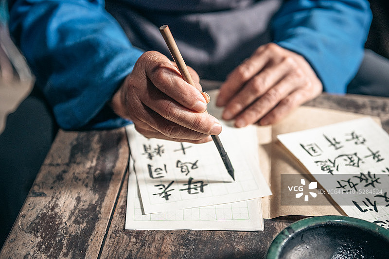 一位中国老人在纸上写书法图片素材