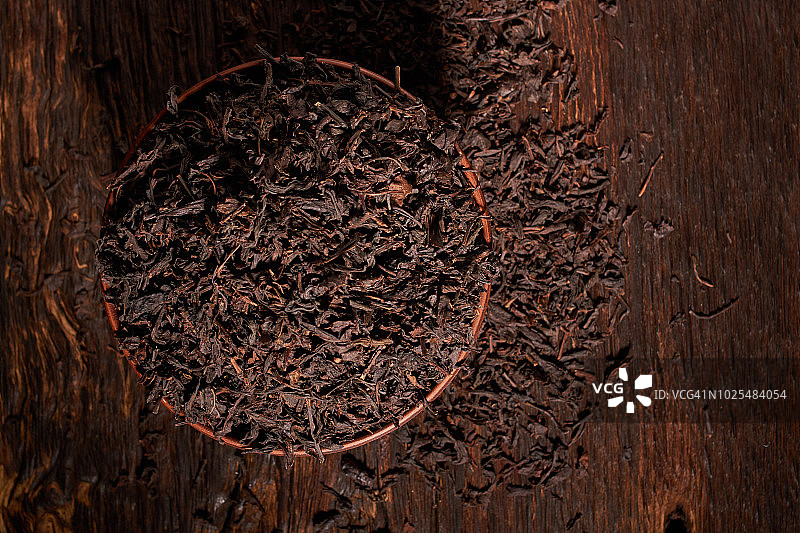 俯视图干红茶在粘土碗在木桌上。茶叶生产的概念。宏,关闭图片素材