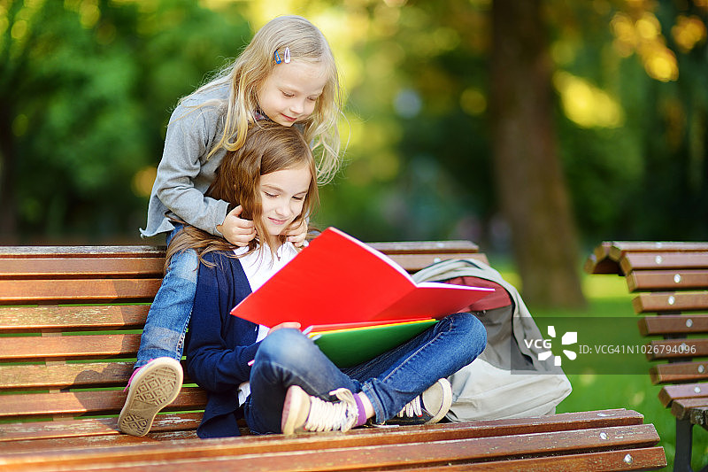 可爱的小女生在晴朗的秋日在户外学习。年轻的学生在做作业。对小孩子的教育。图片素材