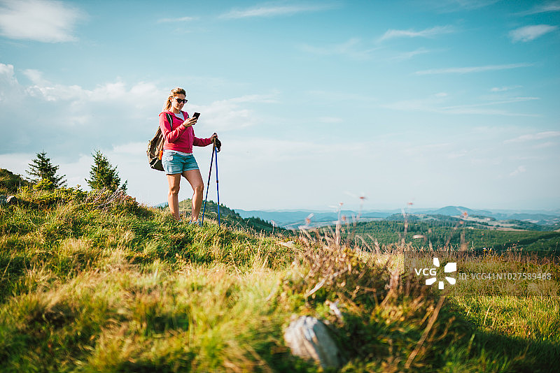 女人在山里徒步旅行，用智能手机找路图片素材