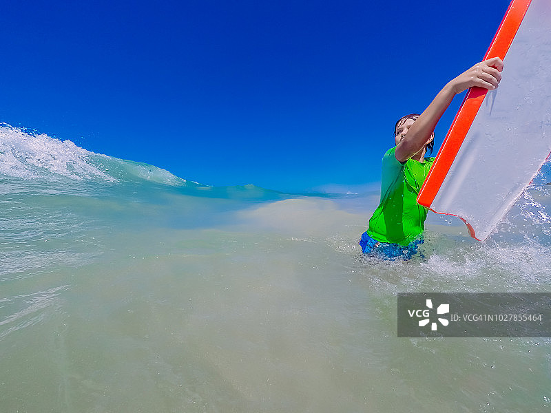 9岁男孩在海滩上冲浪(在大西洋)图片素材