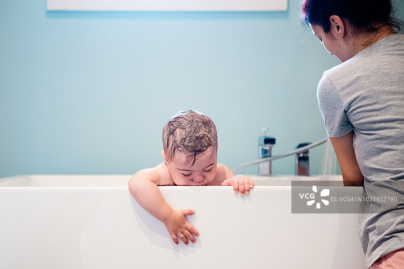 唐氏综合症的小男孩在洗澡，妈妈在给他洗澡。图片素材