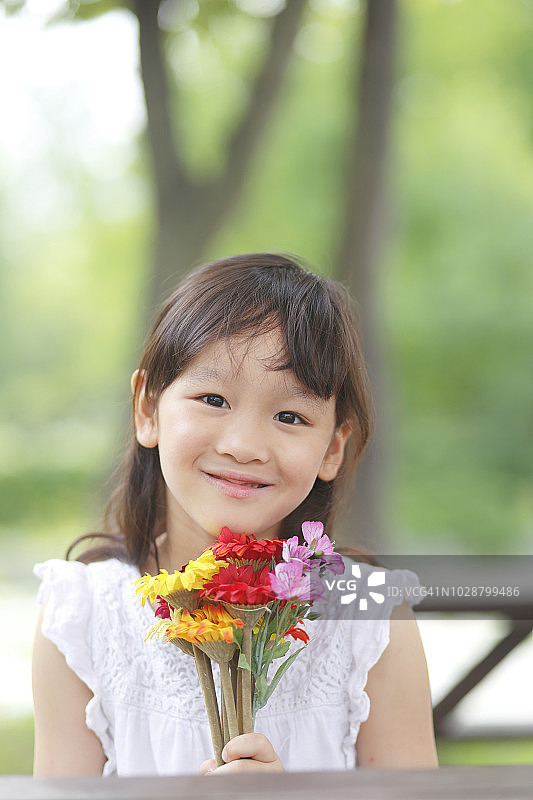 小女孩在公园里捧着花的肖像图片素材