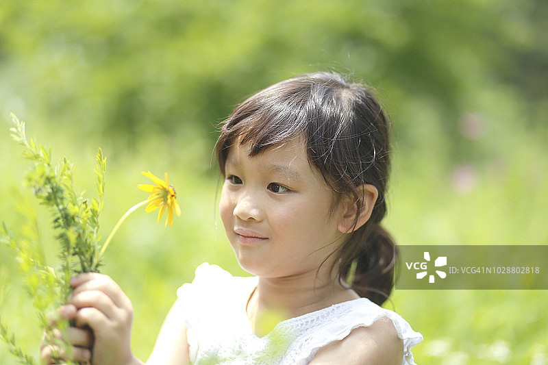 小女孩拿着花在公园里图片素材