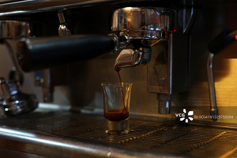 当地咖啡店的浓缩咖啡机将新鲜的咖啡倒入杯子图片素材