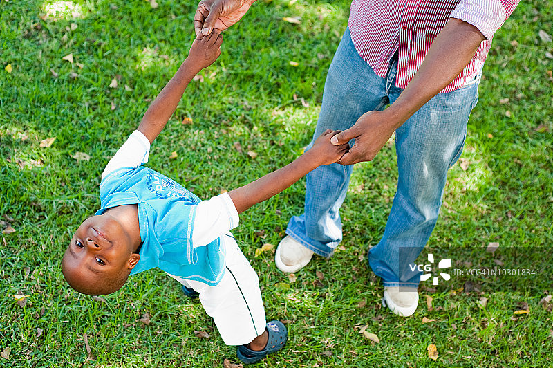 南非豪登省约翰内斯堡，男孩(4-5)和父亲在花园里的草坪上玩耍图片素材