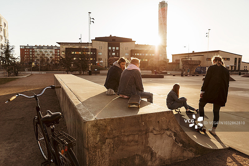 在阳光明媚的日子里，朋友们在城市的滑板公园闲逛图片素材