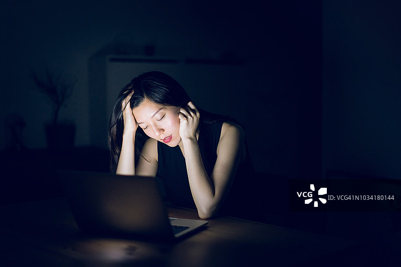 又累又困的女人坐在电脑前工作到很晚图片素材