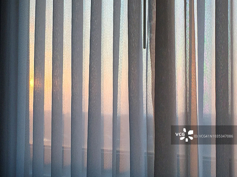 神奇时光:日出时透过褶皱的滑动窗帘图片素材